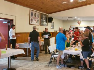 Group gathering in community center with wooden ceiling and decorative lighting.