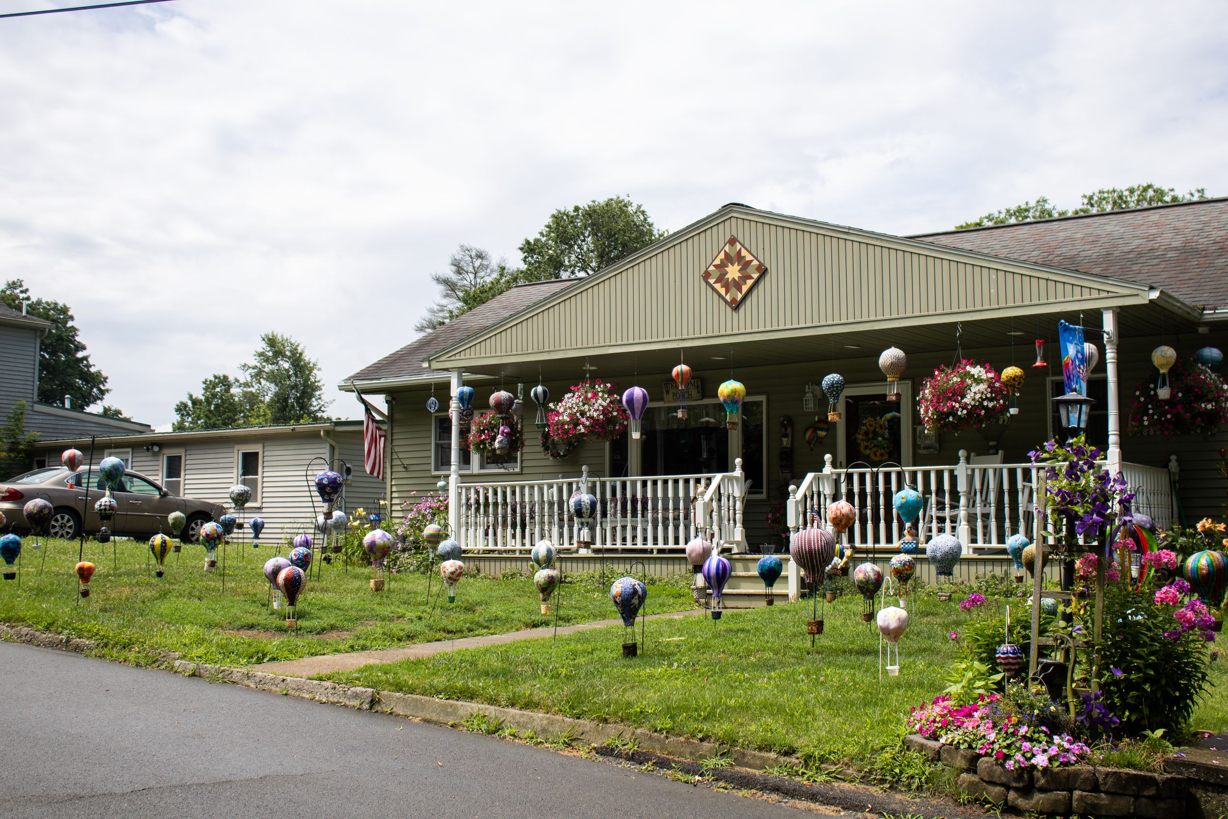 Building exterior decorated with pink flamingos on lawn and covered front porch.