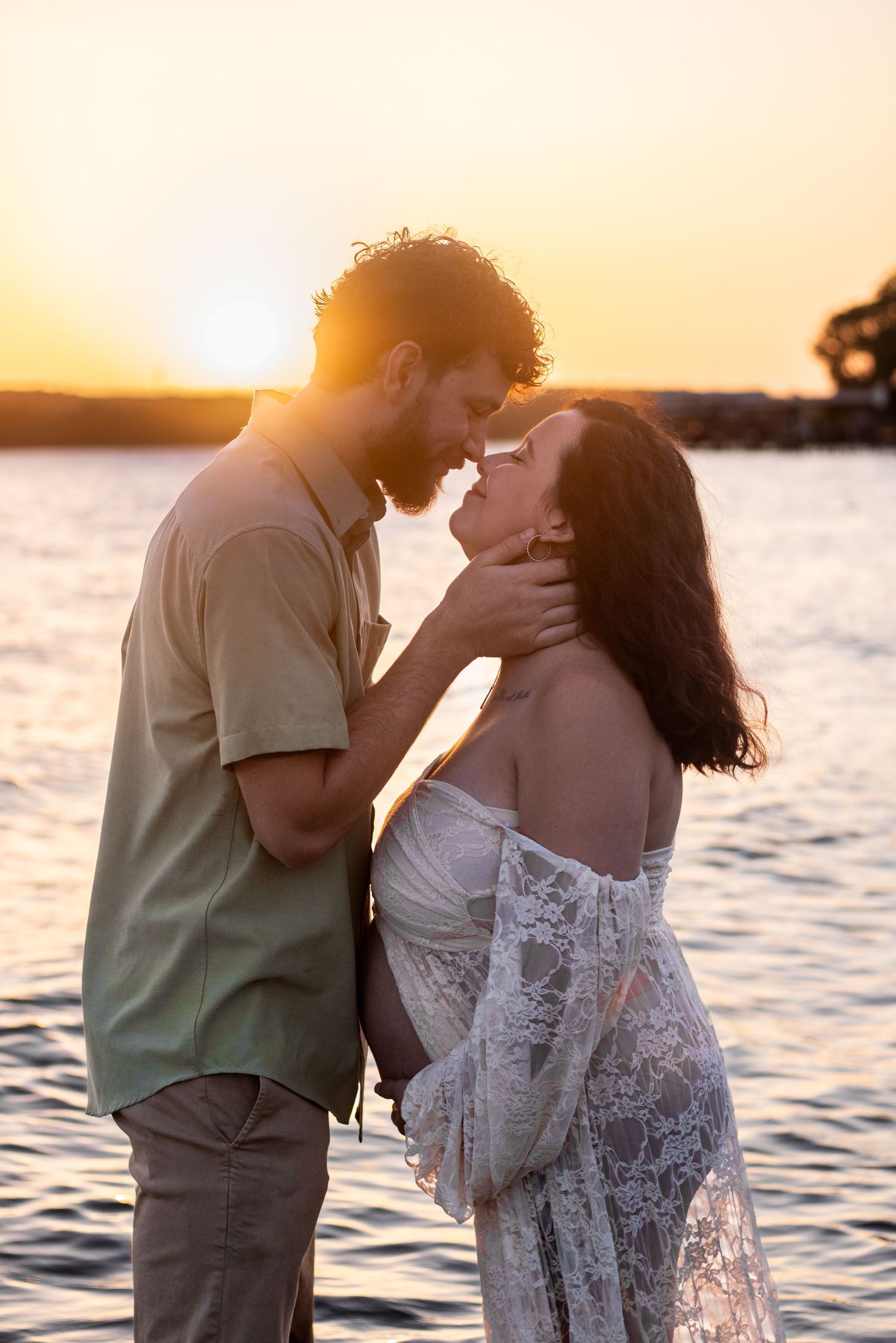 Glowing mom-to-be cradling her baby bump in a golden sunset field, capturing the beauty and anticipation of motherhood.