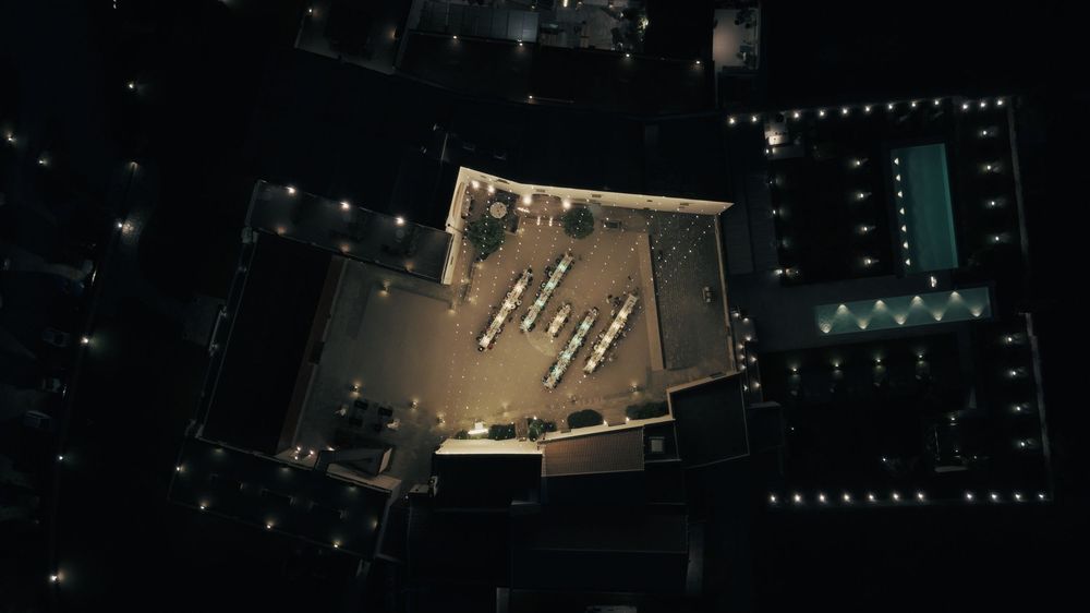 Aerial nighttime view of illuminated city streets and buildings creating geometric patterns in the darkness.
