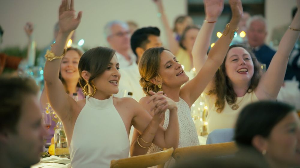 People dancing and celebrating with raised arms at an energetic indoor party event.