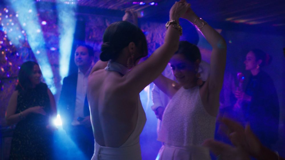 People dancing at a nightclub with bright blue lighting and spotlights illuminating the dance floor.
