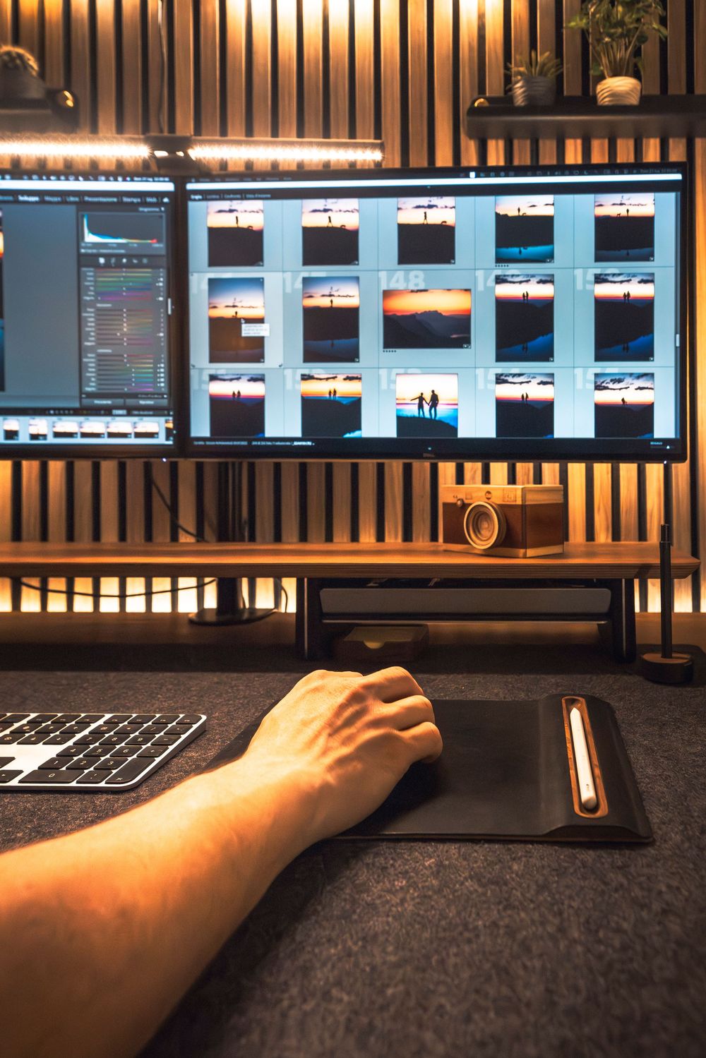 Backlit workspace with computer monitors and keyboard showing someone's hand using the setup.
