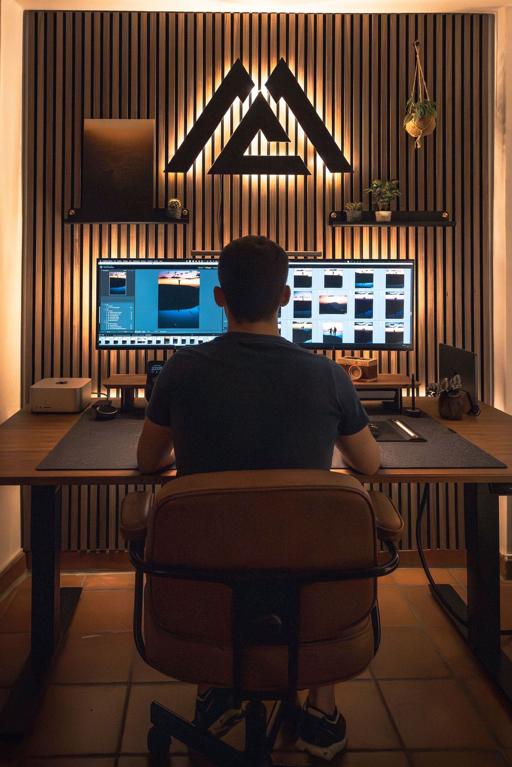 Dimly lit professional editing workspace with multiple monitors and wooden slat wall paneling.
