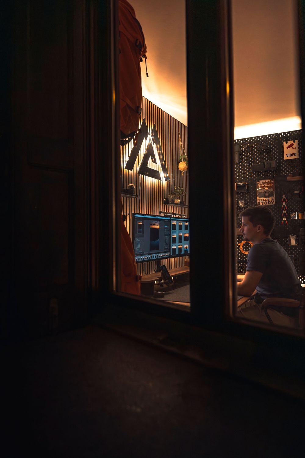 Evening view through windows of an illuminated office workspace with modern design elements.