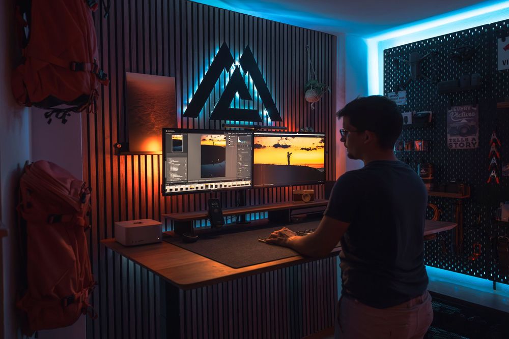 Modern gaming setup with blue LED backlighting on multiple monitors and peripherals in a dimly lit room.