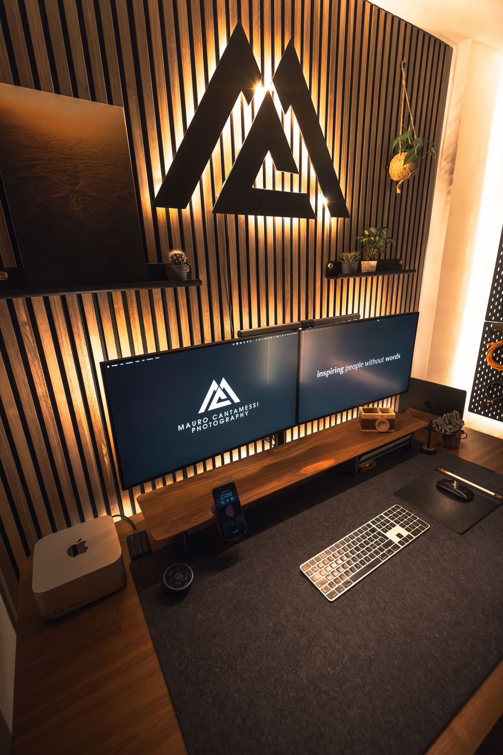 Modern desk setup with illuminated wall panels and Apple products in a sleek workspace environment.