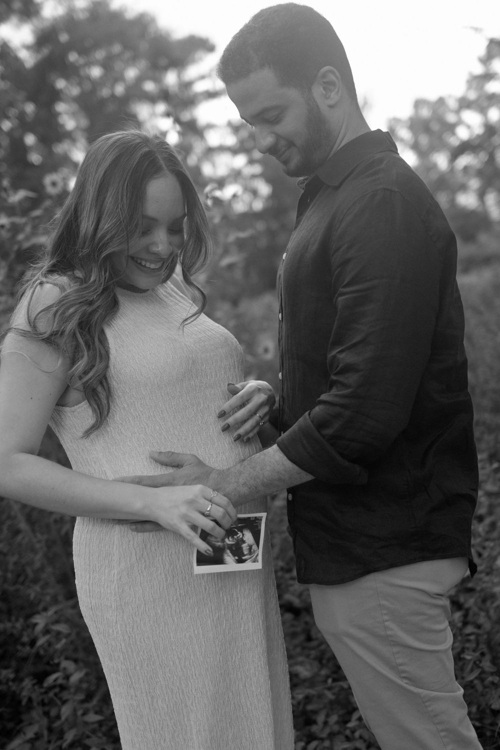 Couple examining ultrasound photo together in outdoor black and white portrait.
