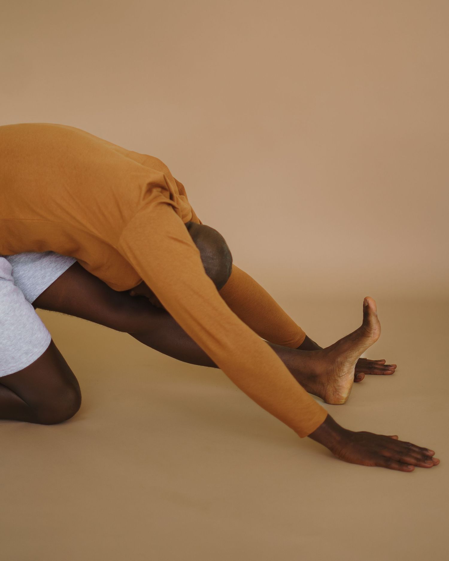 Multiple hands in orange gloves demonstrate a sequence of hand movements over a beige surface.