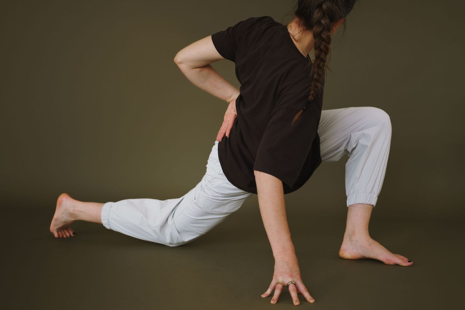 Dancer in black shirt and white pants performs contemporary dance move on dark background.