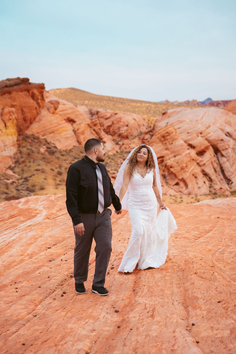 Newlyweds share a dramatic moment against vibrant desert rock formations at sunset.
