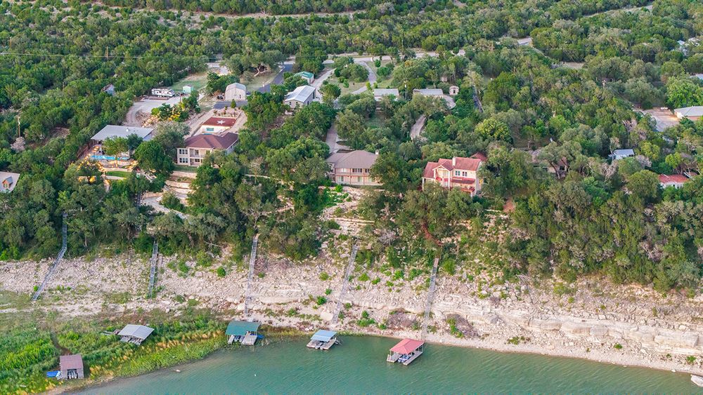 A scenic aerial panorama reveals turquoise waters and rocky coastlines dotted with homes along the Mediterranean shoreline.