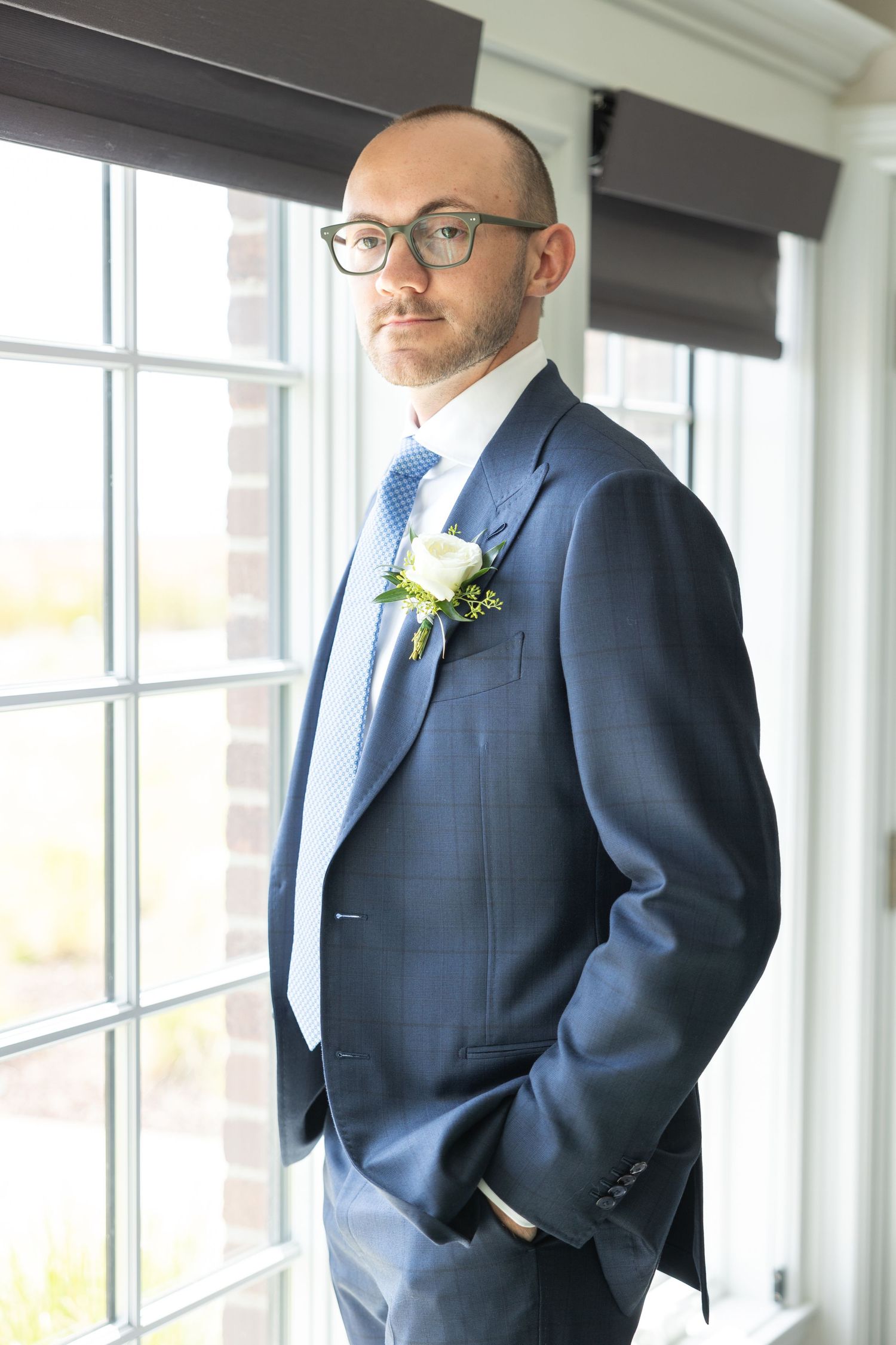 A groom in a dark navy suit stands by bright windows in three similar posed photographs. Rachel Martinez Photography Metro Detroit Photo