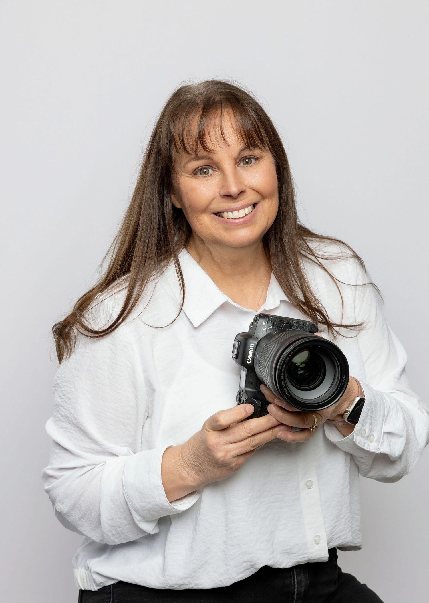Photographer demonstrates camera handling techniques in white studio setting.