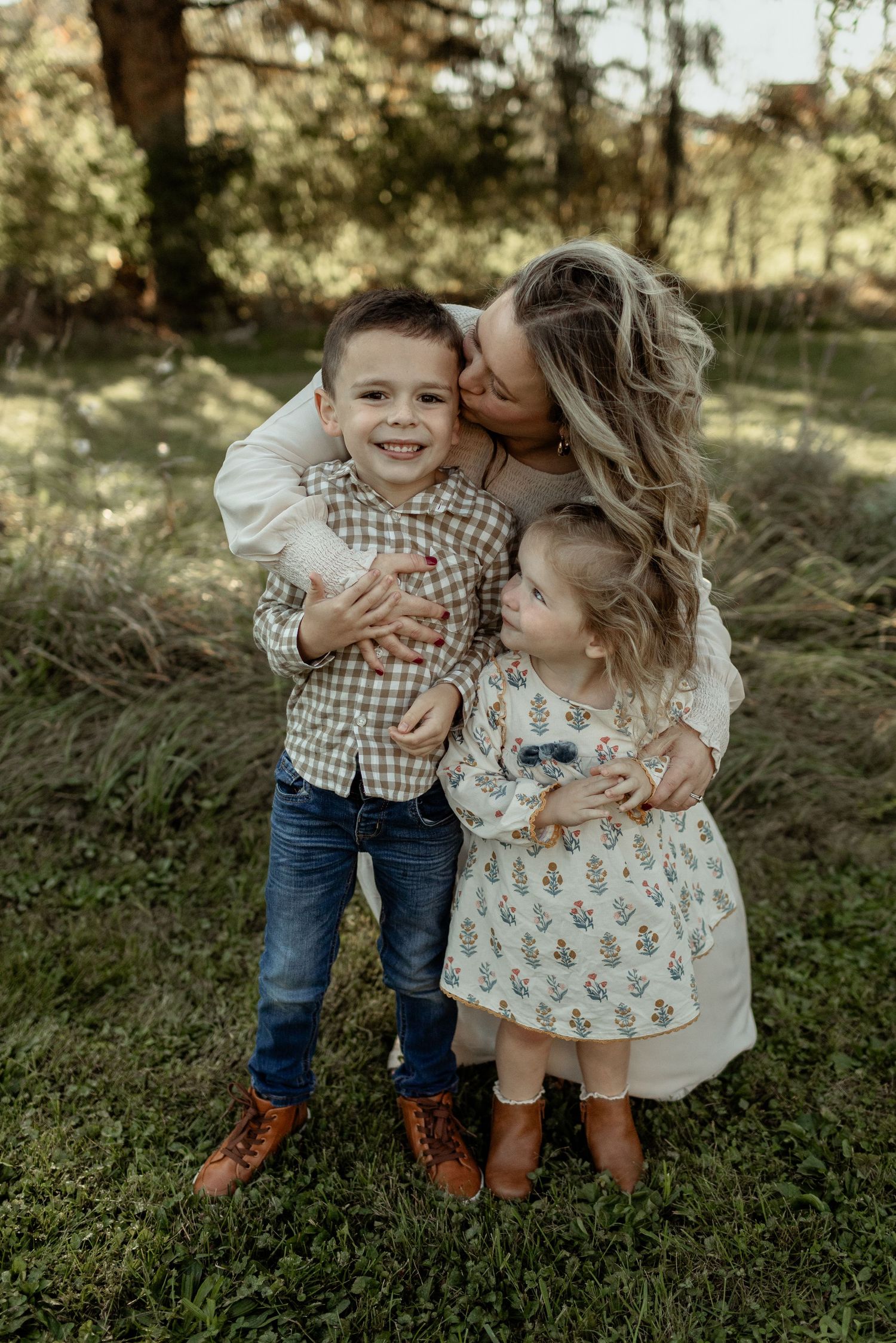A candid moment of play and affection between family members in a sunlit garden setting among greenery.