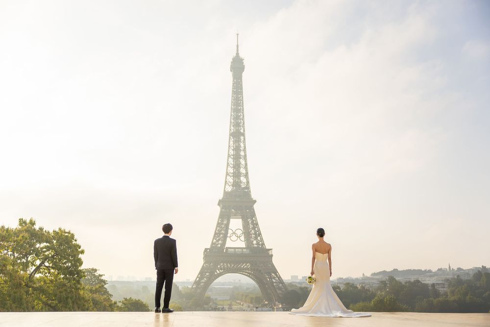 Wedding couple admiring Eiffel Tower from Trocadero viewing platform in Paris at sunset.