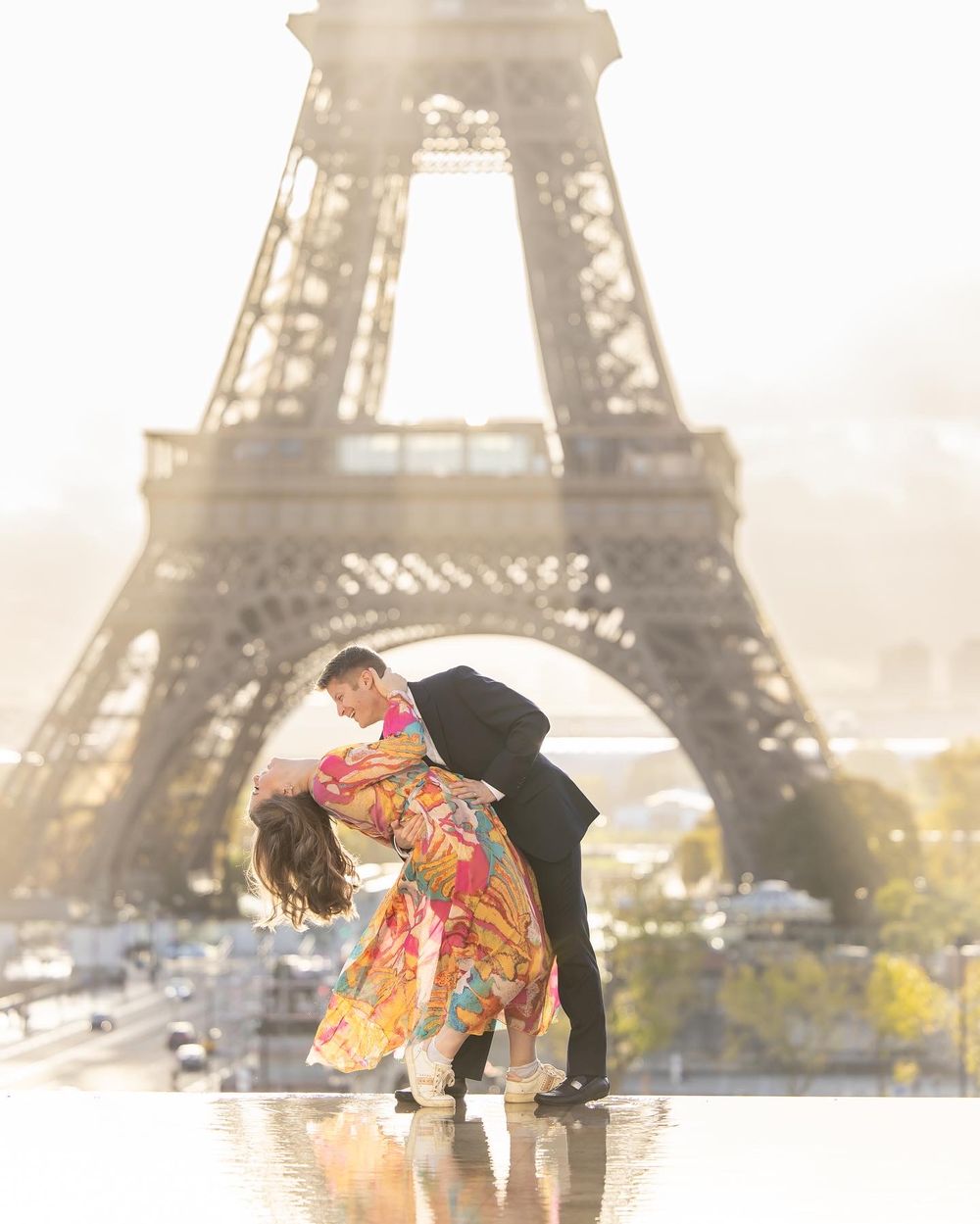 A romantic moment captured in a colorful dress dipping pose in front of the iconic Eiffel Tower at sunset.