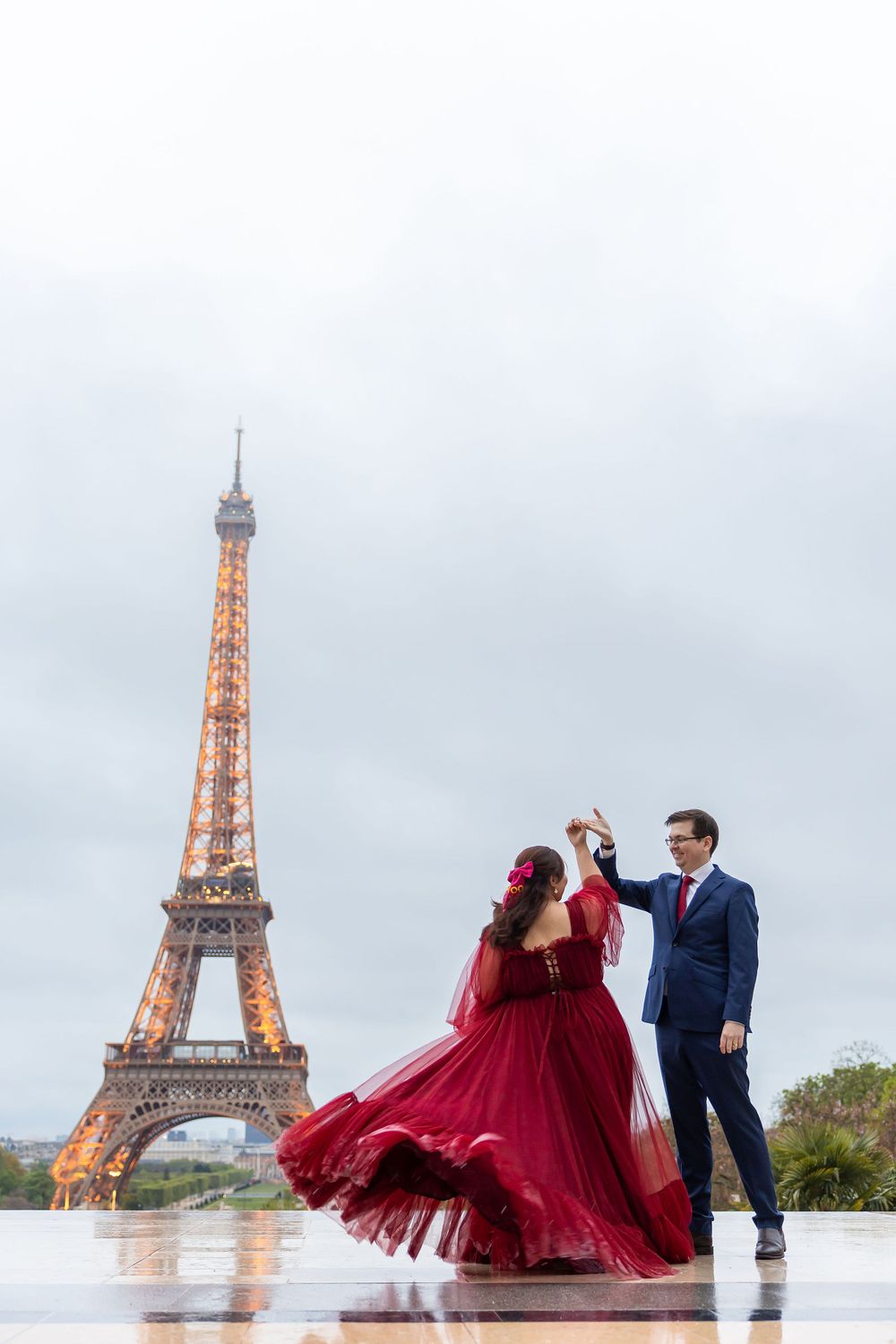 A couple dancing at Trocadero Plaza with the illuminated Eiffel Tower glowing in the background during dusk in Paris.