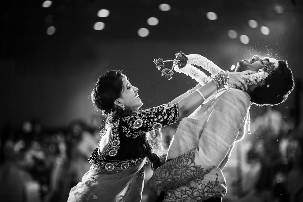 Black and white photo of an Indian bride placing a garland on the groom during their engagement ceremony in Wellington, New Zealand