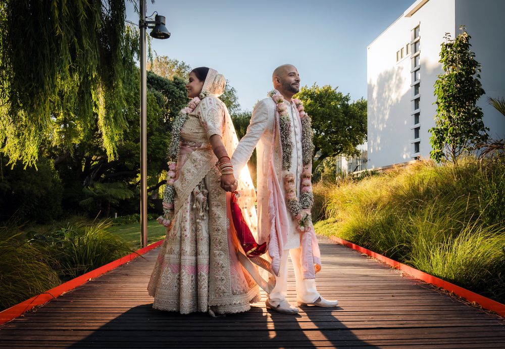 Indian couple holding hands and looking in opposite directions during a sunset wedding couple session in Wellington, New Zealand.