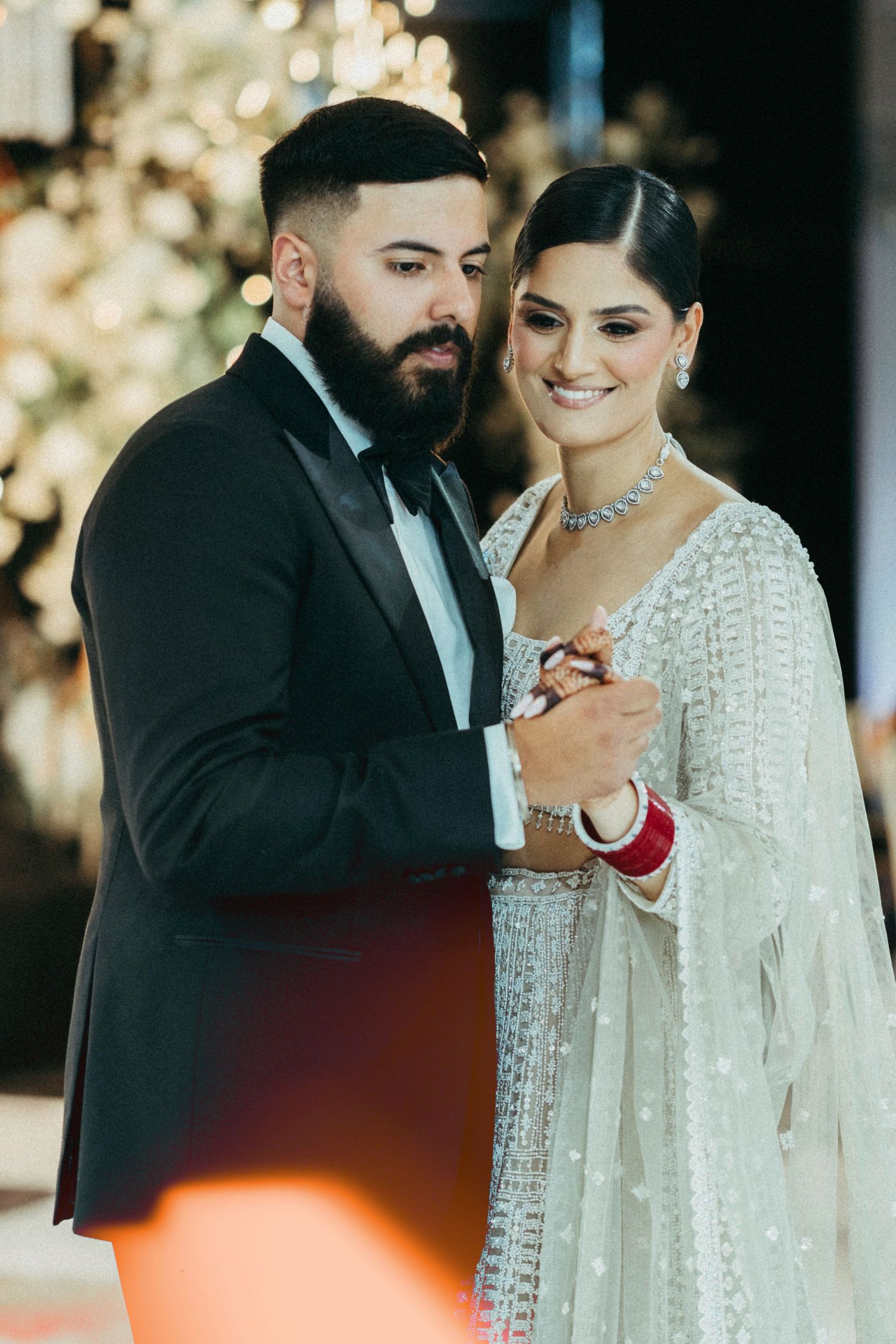 A couple shares an intimate dance moment at their wedding reception, with the bride in white and groom in a black tuxedo.
