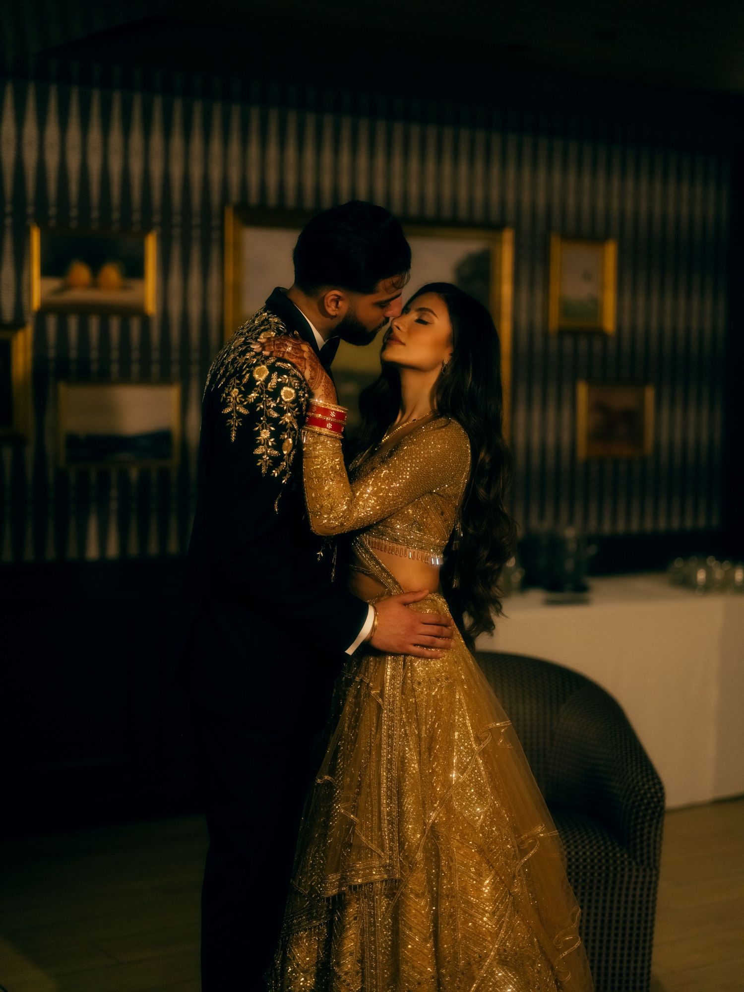 A couple shares an intimate dance moment in golden evening light while wearing traditional Indian wedding attire.