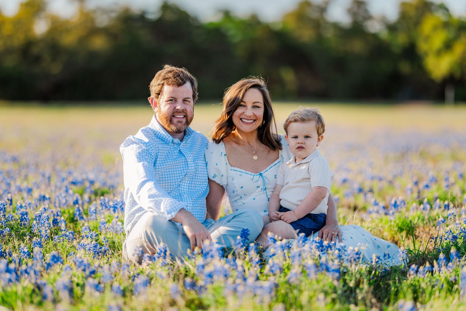 Family posing together in bluebonnet field for a spring mini session in Central Texas with vibrant wildflower backdrop.