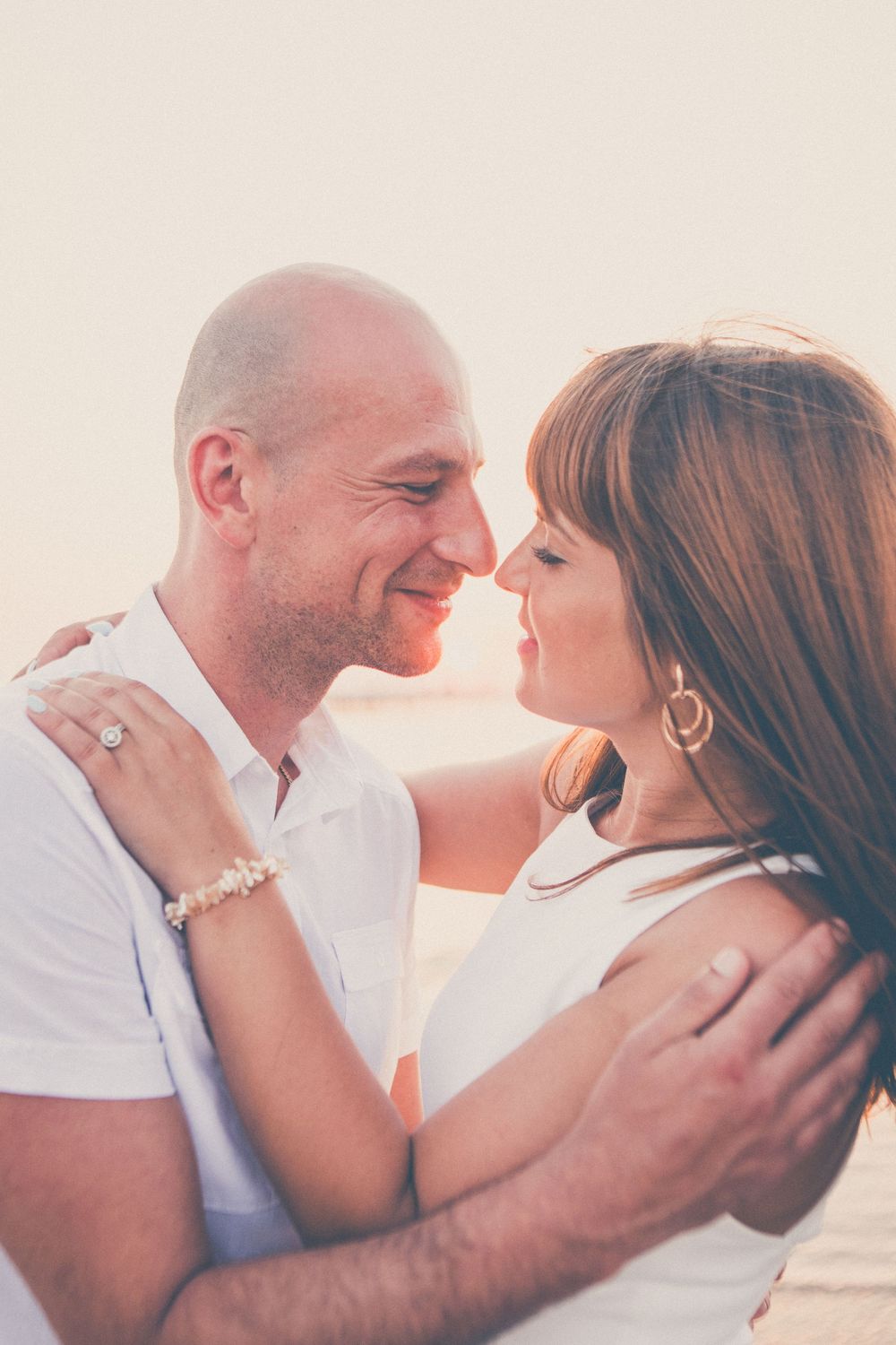 A romantic couple embraces in a series of intimate poses against a soft, dreamy background during sunset.