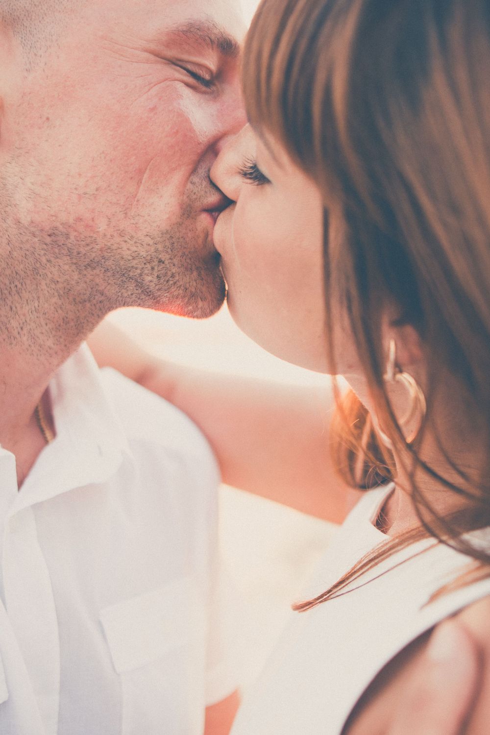 A tender romantic moment captured in soft lighting as a couple shares an intimate kiss.