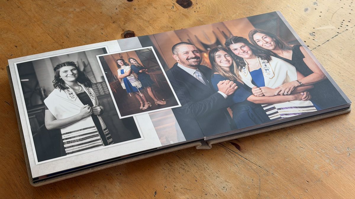 Several black and white photo albums and prints laid out in sequence on a rustic wooden surface.