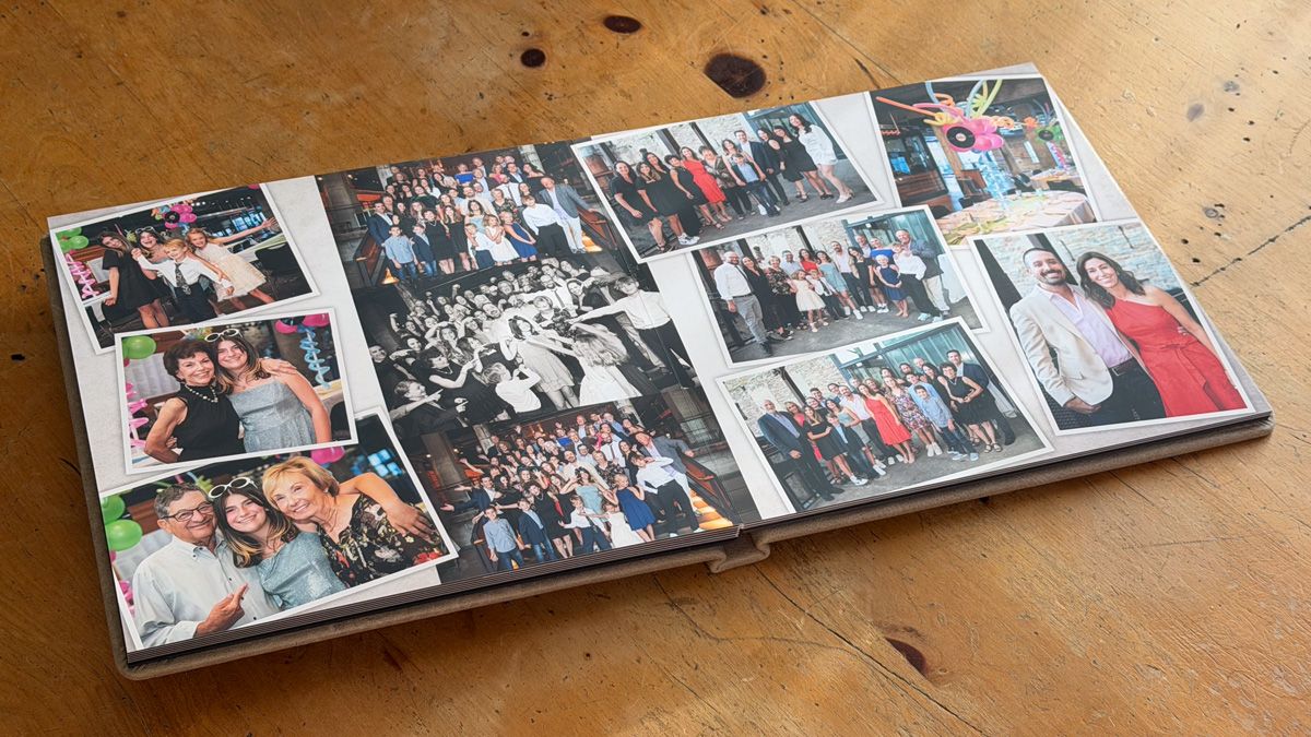 Photo album lying open on wooden surface showing collection of group photos and memories arranged across pages.