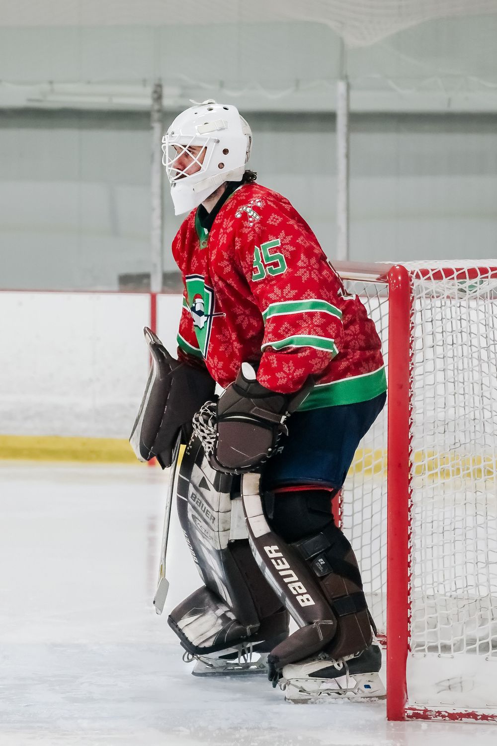 Ice hockey goalie stretches to make a save in front of the net during a game.