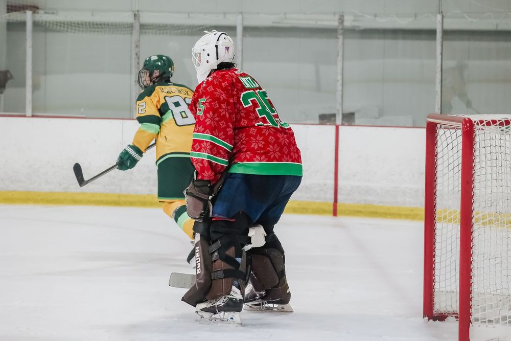 Hockey players in action on the ice with red goal posts visible in the background.