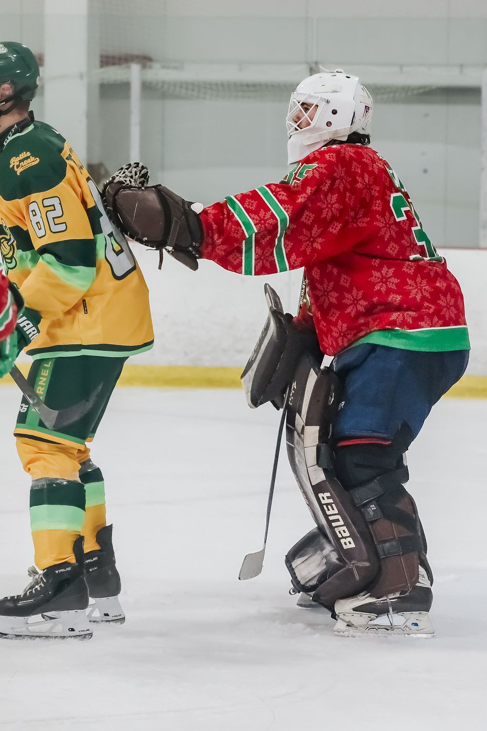 Hockey players in yellow and red jerseys battle for position on the ice.