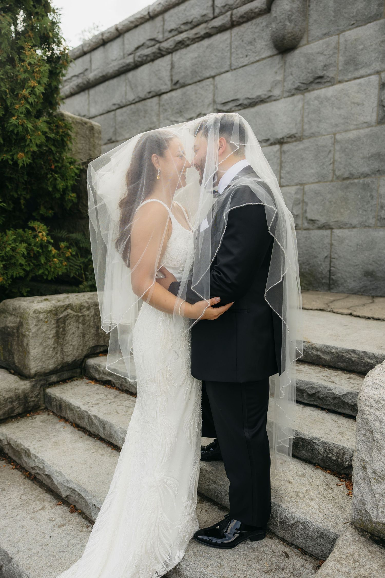 A romantic wedding couple shares an intimate moment on stone steps against a stone wall backdrop in Chicago Lincoln Park