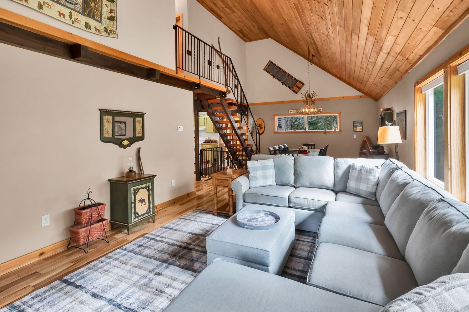 Modern bedroom with wood plank ceiling, gray bedding, and a cozy seating area showcasing rustic mountain lodge decor.