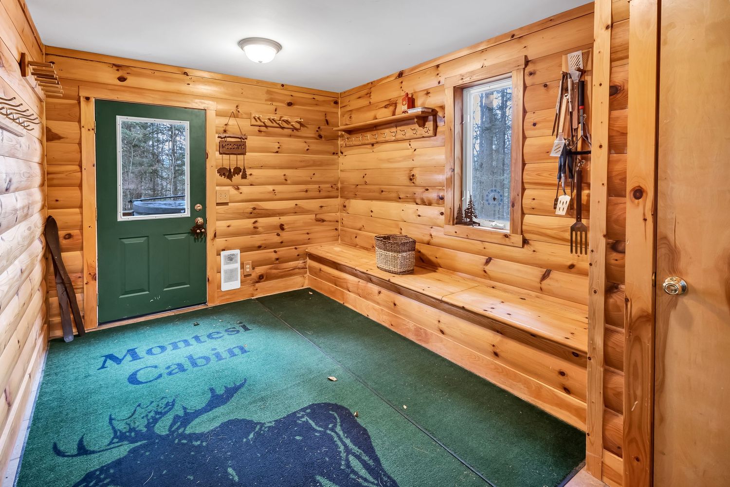 Mudroom with pine wood walls, green carpet, built-in bench seating, and mountain-themed floor design.