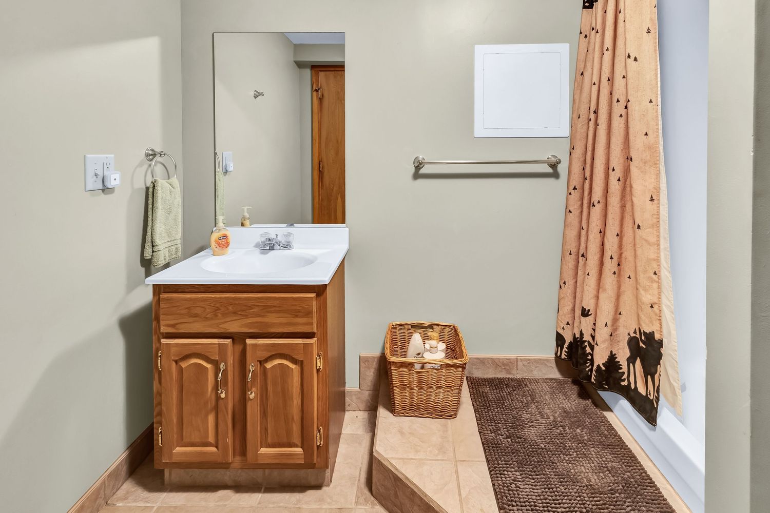 Clean bathroom interior with wooden door, peach curtains, and white fixtures against light grey walls.