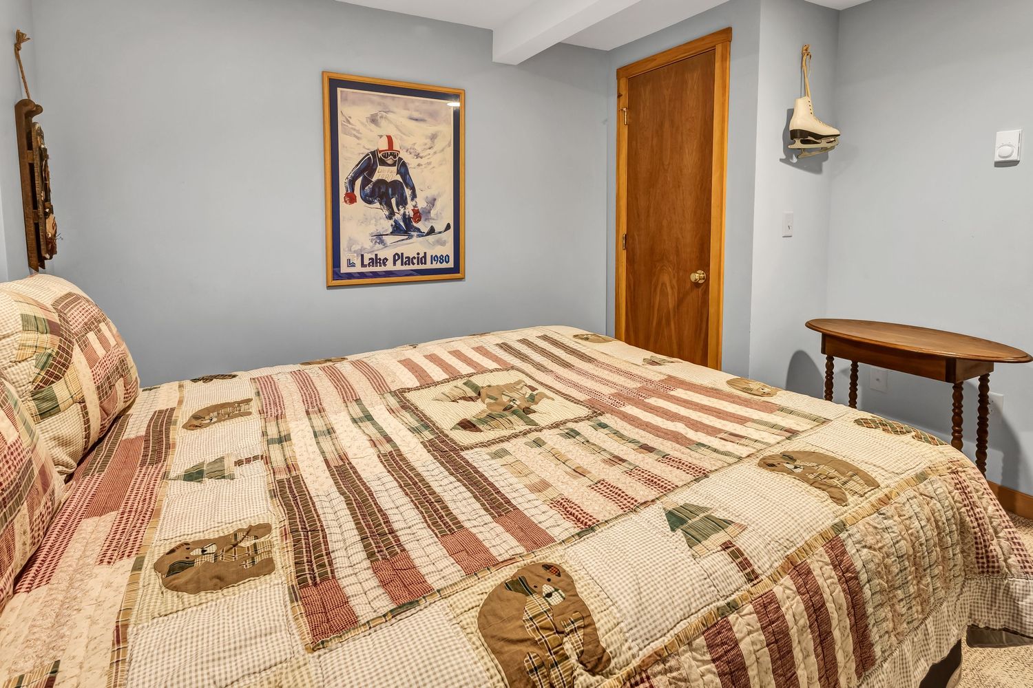 Rustic bedroom with patterned quilt bedding, wooden furniture, and country-style decor on the walls.