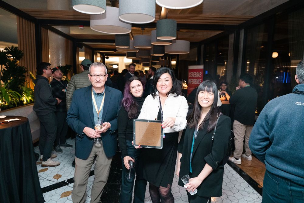 Professional networking event with groups of people mingling and socializing in a modern indoor venue with ambient lighting.