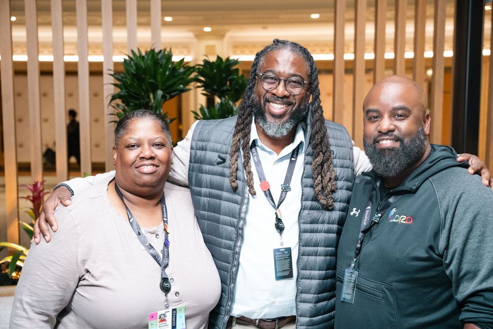 A group of people gather together smiling and posing at what appears to be a professional conference or event.