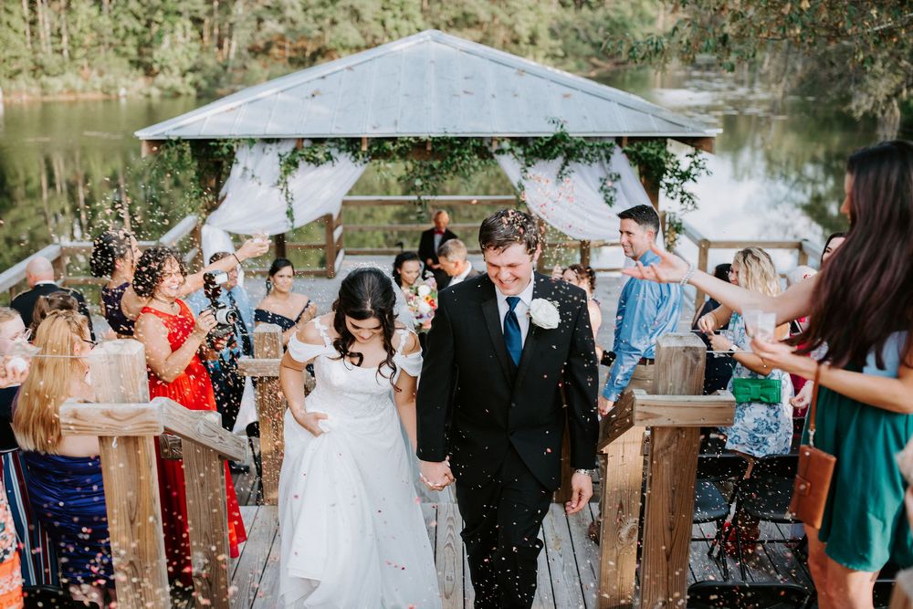 Wedding celebration outdoors with guests throwing confetti under a white canopy.