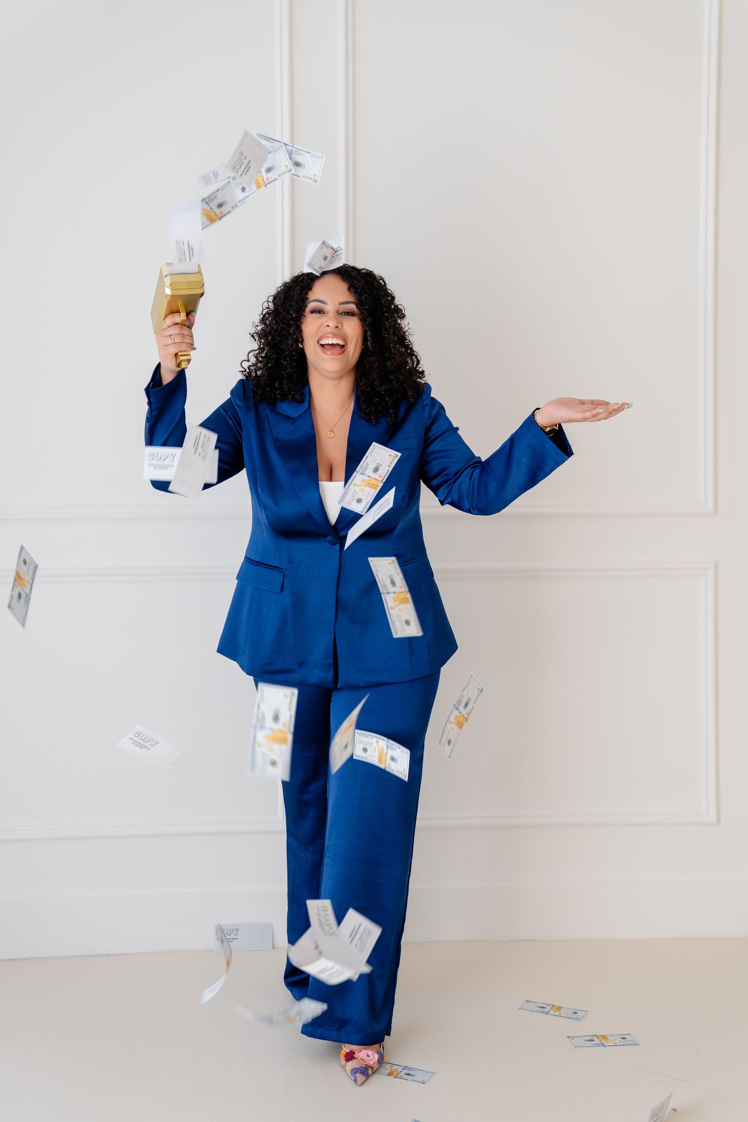 Person in vibrant royal blue business suit poses playfully with curly hair against white background.