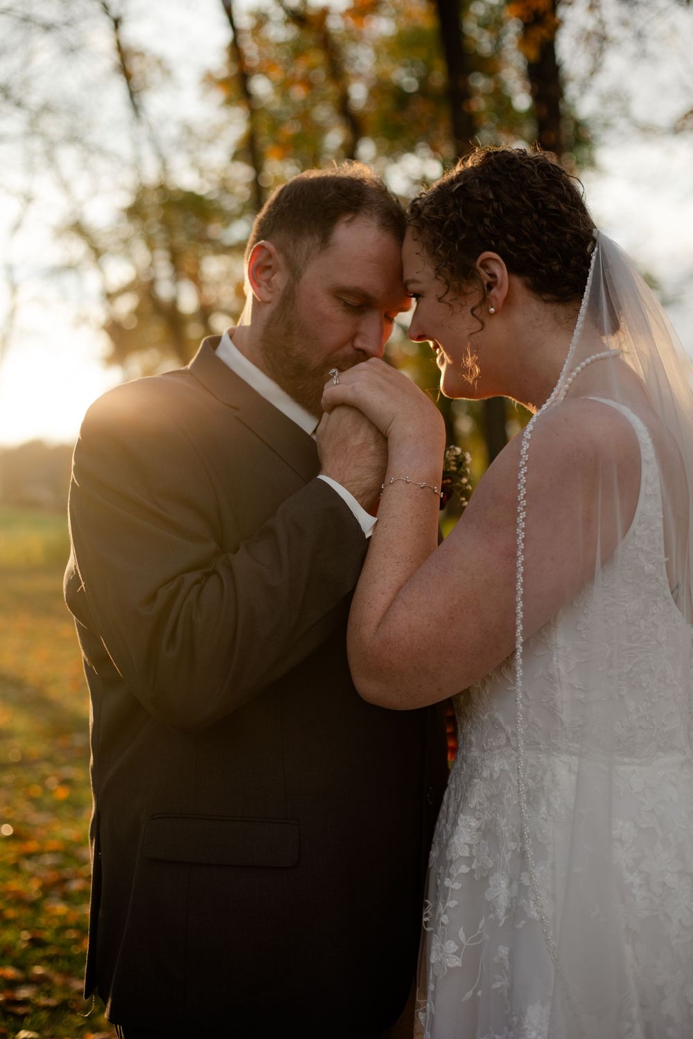 A tender moment between newlyweds during sunset with autumn foliage in the background.