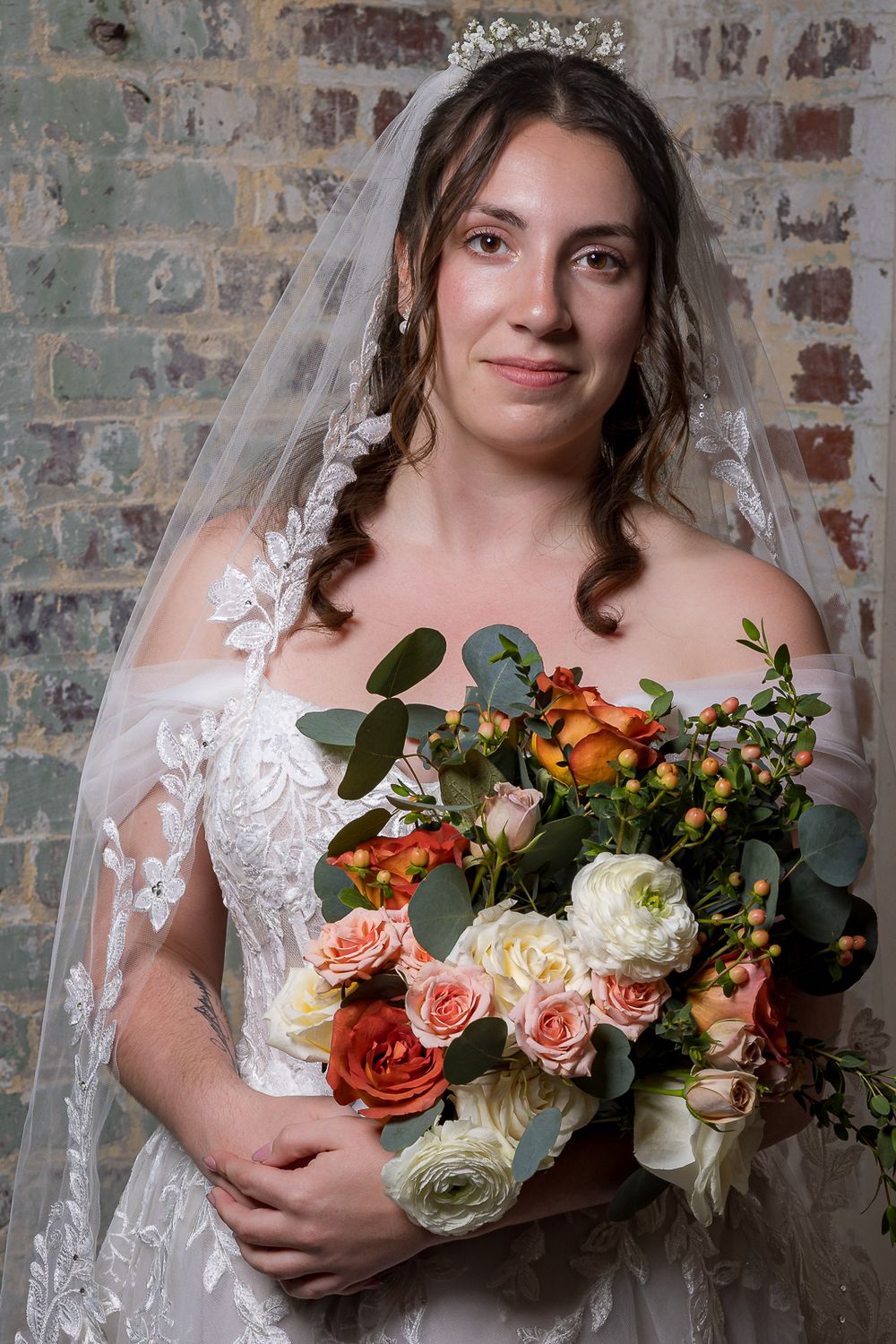 A bridal portrait series showing a lace-detailed dress and autumn-toned bouquet against a rustic brick wall.