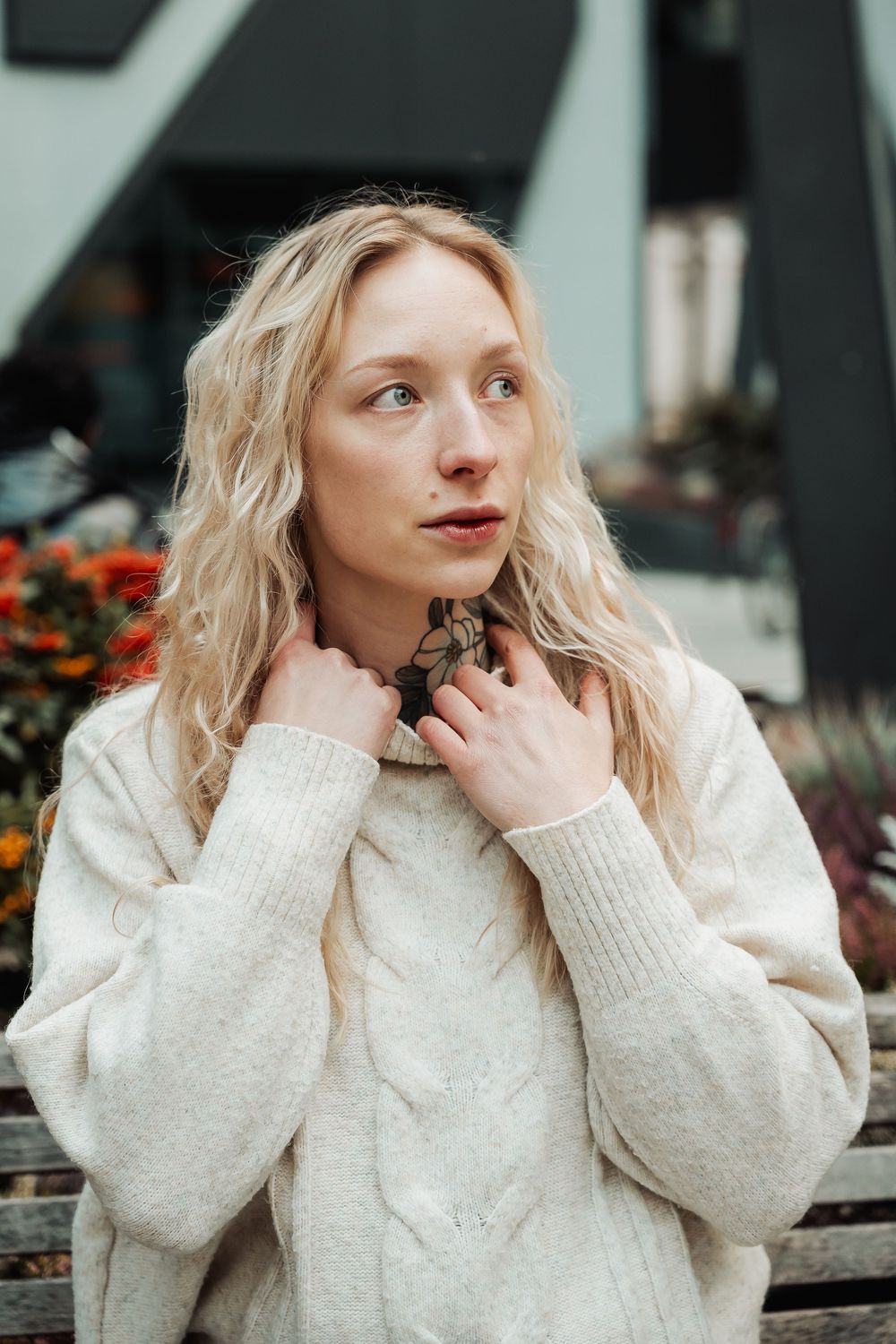 A person in a cream knit sweater poses thoughtfully with hand near face in a series of candid outdoor shots.