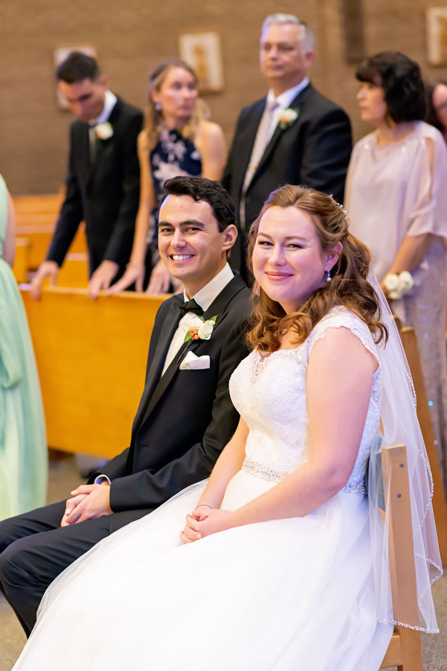 A wedding ceremony scene with guests seated in rows while a couple shares a joyful moment at the altar.