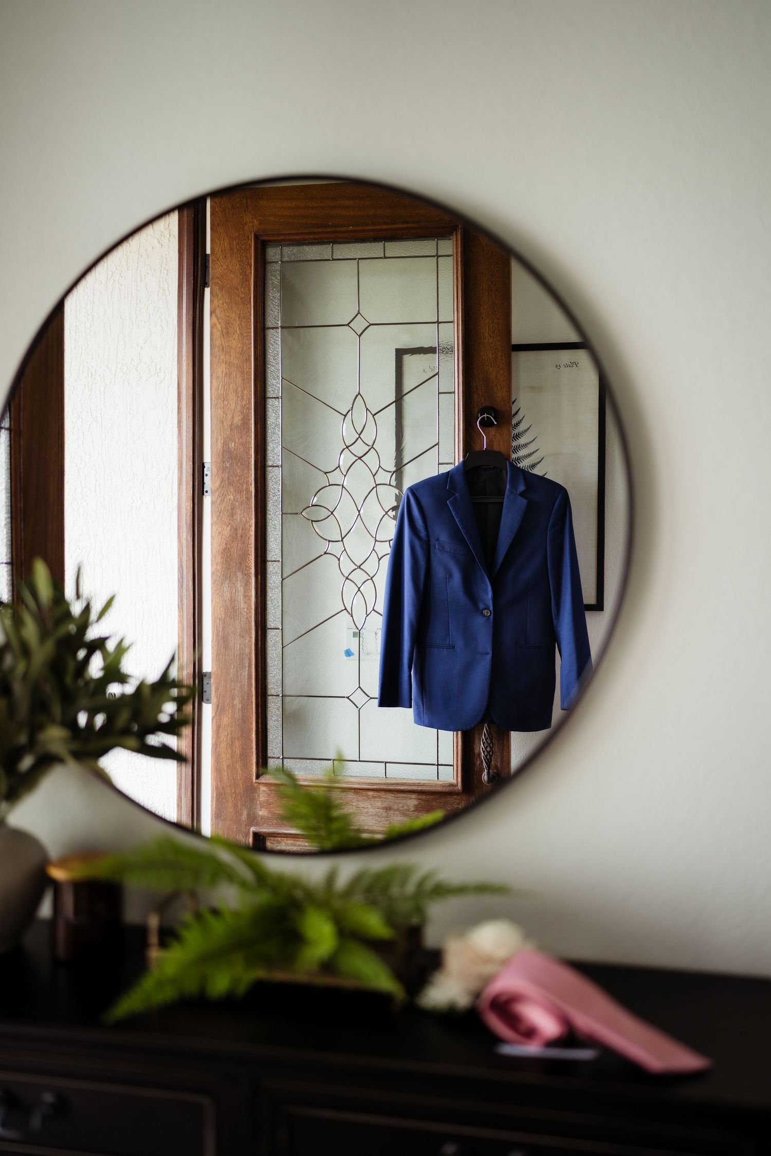 A series of oval mirrors on a wall reflect a blue garment and interior decor elements.