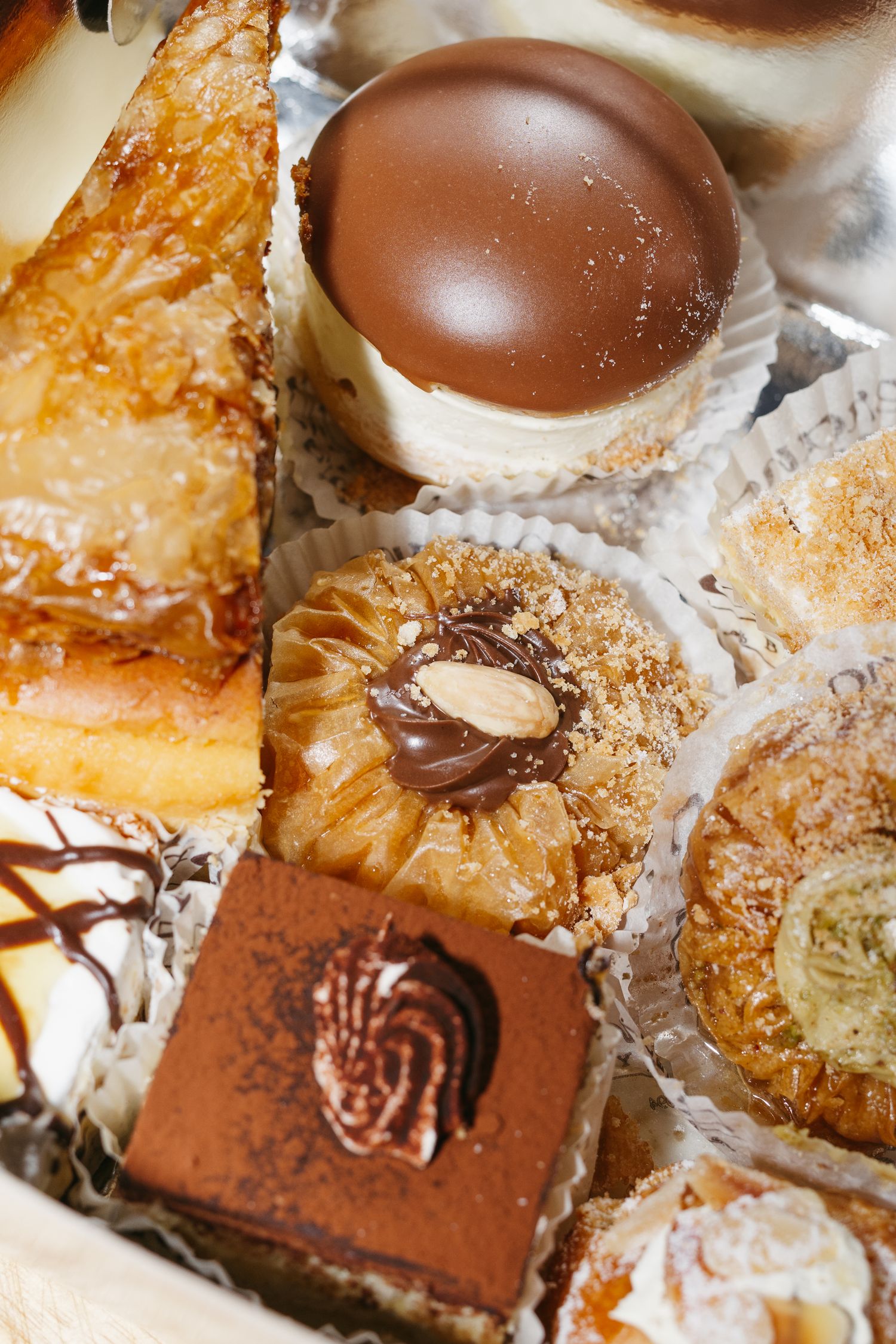Assorted luxury pastries and chocolates in a gift box, including tiramisu, baklava, and chocolate truffles.