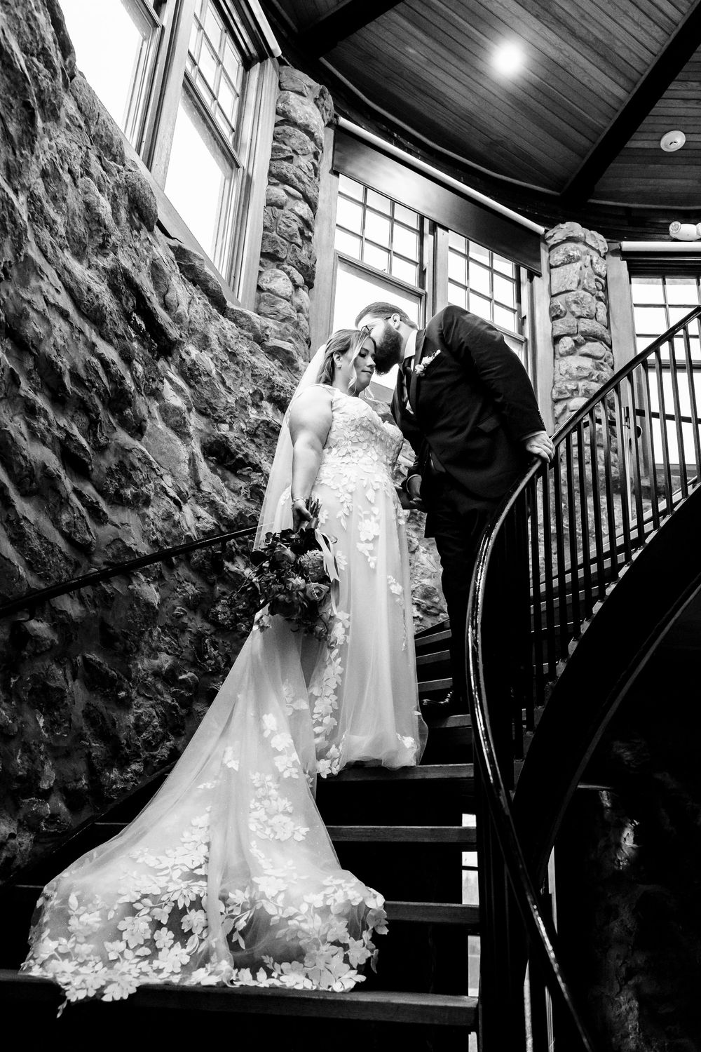 Romantic wedding scene on stone staircase with dramatic lighting and elegant white gown details.